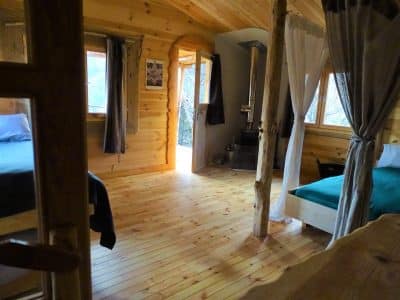 Cabane en bois chaleureuse avec un intérieur lumineux et des lits confortables.