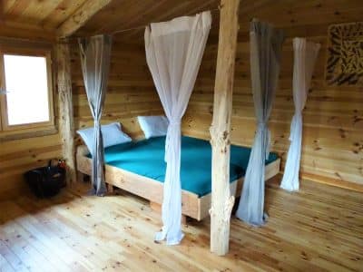 Chalet en bois avec lit à baldaquin et décor naturel en Auvergne-Rhône-Alpes.