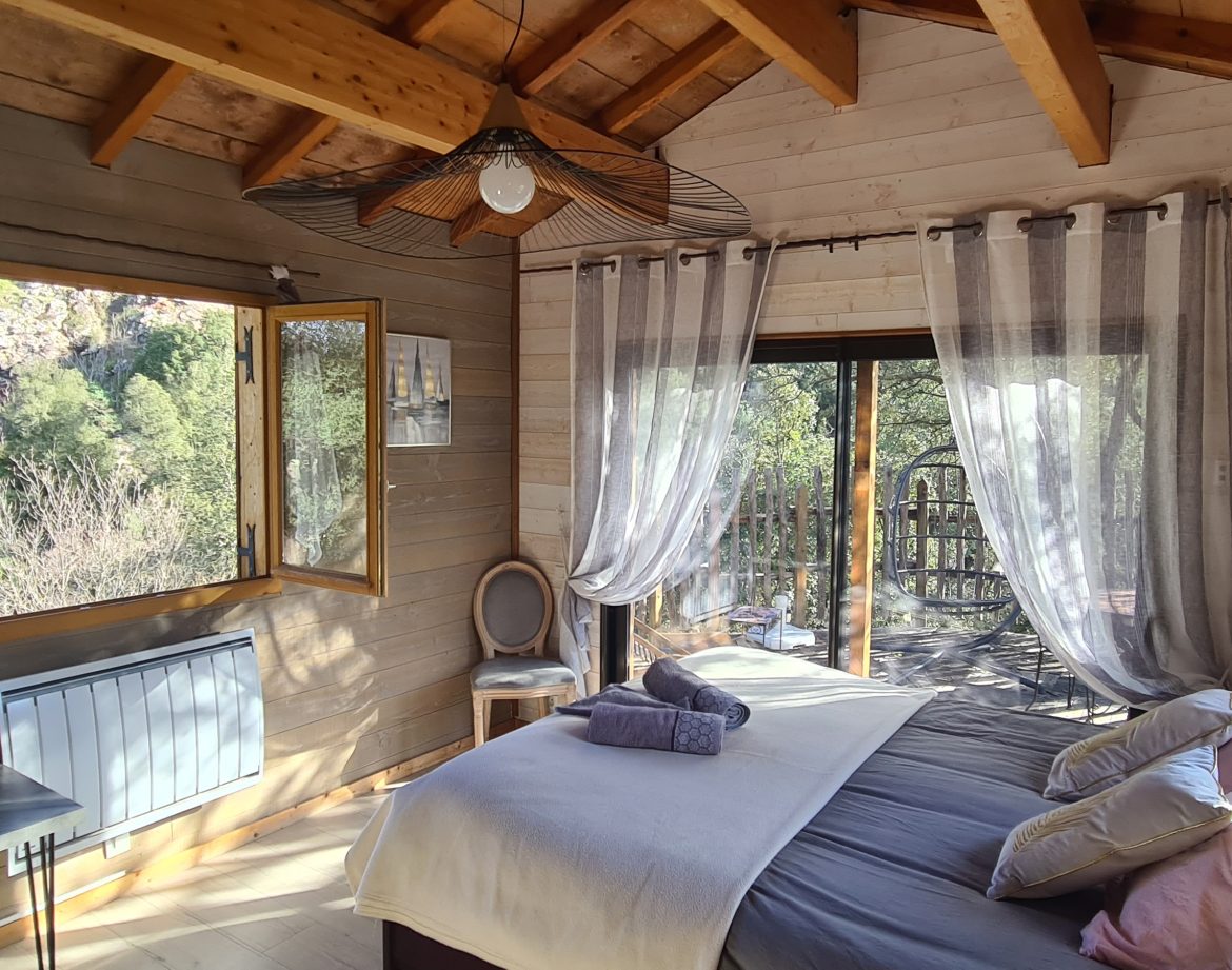 Cabane en bois en Corse, avec de grandes fenêtres et une vue sur la nature.