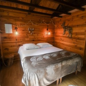 Chalet en bois chaleureux avec lit douillet et décoration en bois naturel.