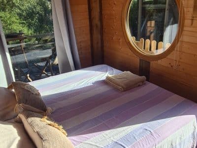Chalet en bois à Corse, avec un lit confortable et une fenêtre ronde accueillante.