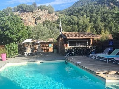 Hébergement insolite en Corse avec piscine et vue sur les montagnes verdoyantes.