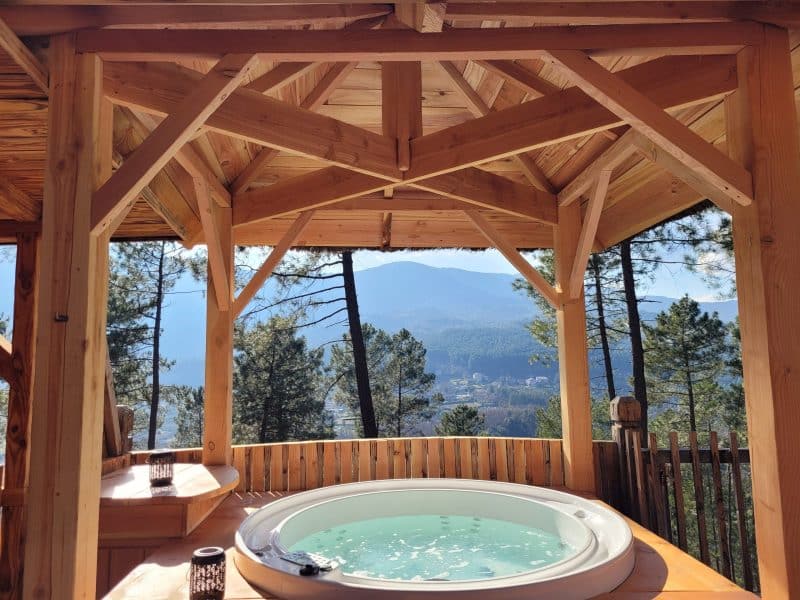 Cabane en bois avec jacuzzi, offrant une vue panoramique sur la montagne.