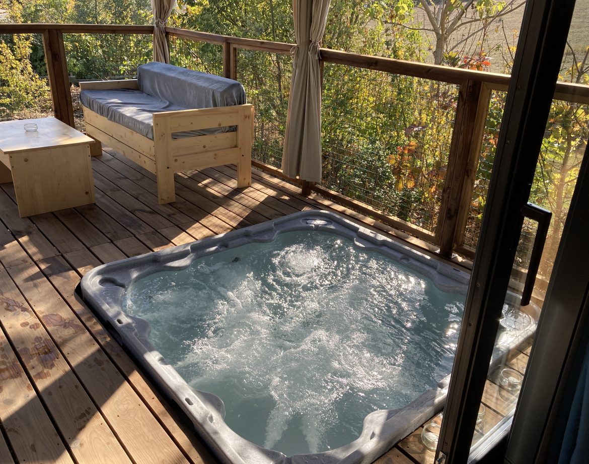 Cabane perchée en Languedoc-Roussillon avec jacuzzi sur la terrasse en bois.