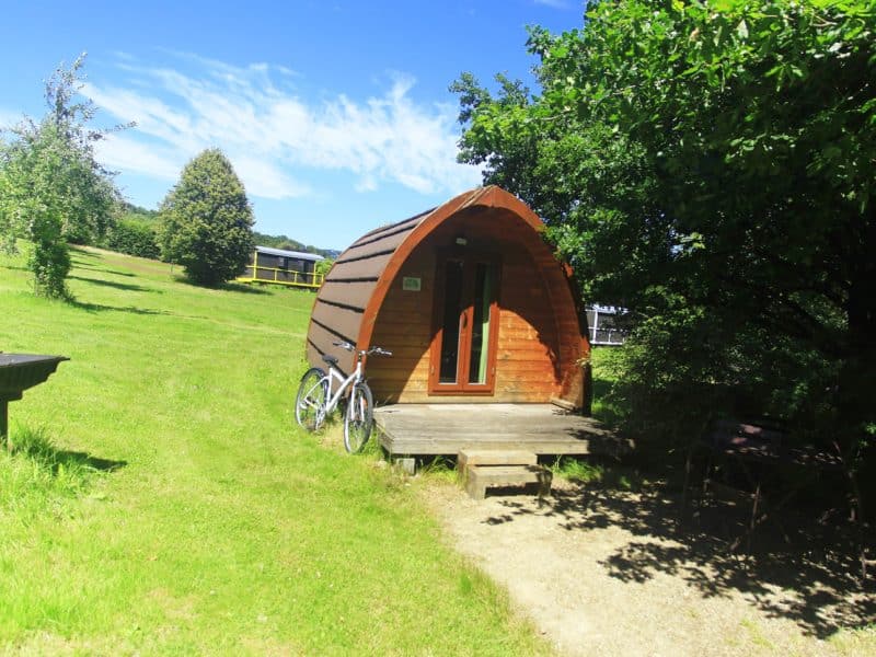 Cabane en bois avec terrasse, entourée de verdure et de paysages apaisants.