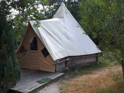 Tente safari spacieuse à Grand-Est, avec un toit en toile et une terrasse en bois.