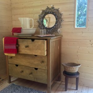 Hébergement insolite en Basse-Normandie : intérieur en bois avec meuble vintage et miroir décoratif.