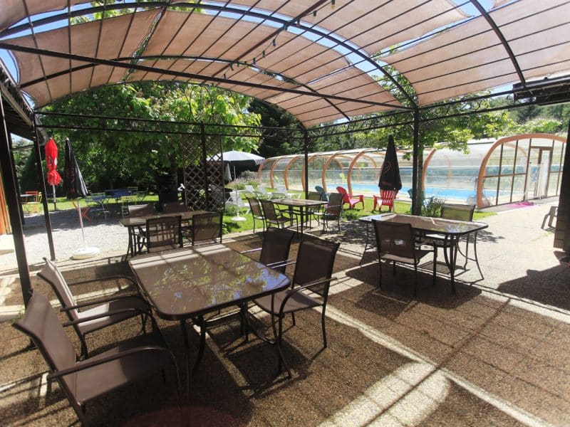 Chalet accueillant avec terrasse ombragée et piscine couverte, idéal pour se détendre.