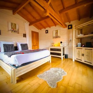 Chalet en bois chaleureux avec un lit douillet et un plafond en poutres apparentes.