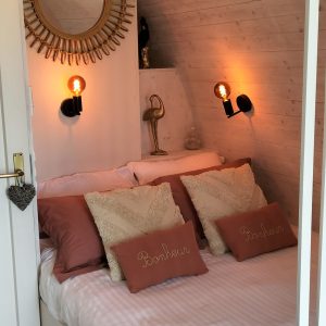 Chambre cocooning dans un hébergement insolite, décorée avec un miroir doré.