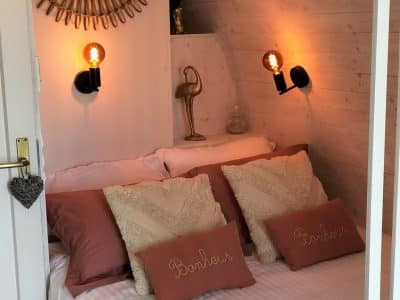 Chambre cocooning dans un hébergement insolite, décorée avec un miroir doré.
