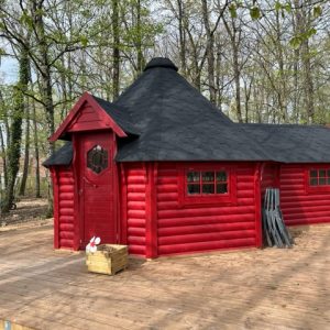 Cabane en bois rouge, entourée de verdure, idéale pour un séjour insolite en Île-de-France.