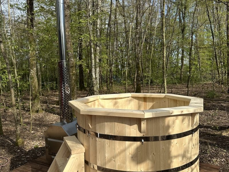 Hébergement insolite : bain nordique en bois entouré de verdure apaisante.