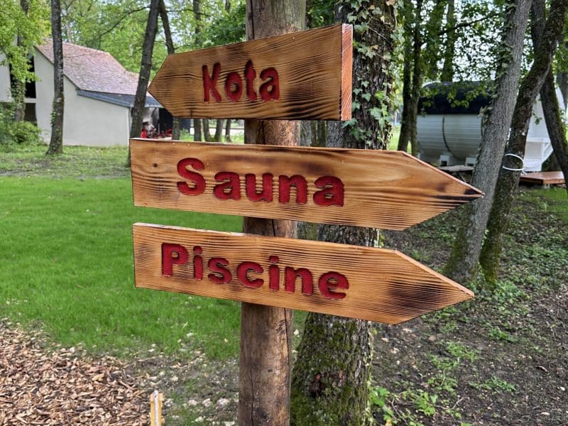 Hébergement en pleine nature avec panneaux directionnels vers sauna et piscine.