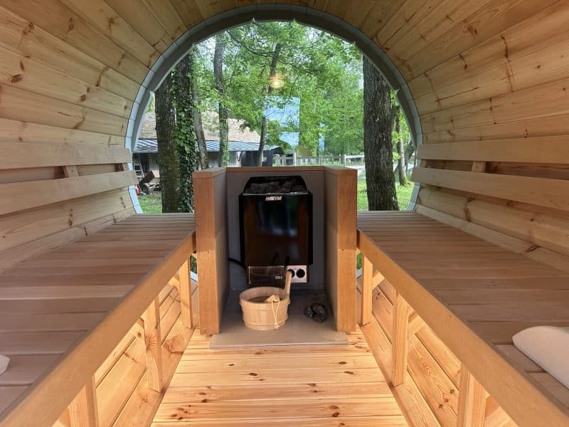 Intérieur dun hébergement en bois, avec bancs et vue sur la nature verdoyante.