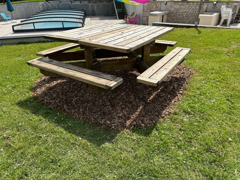 Table de pique-nique en bois entourée de pelouse, idéale pour un hébergement en plein air.