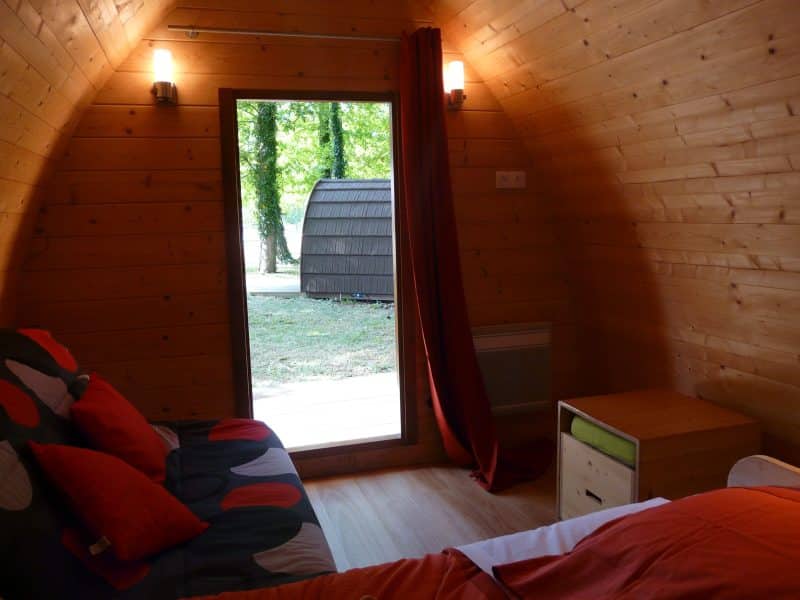 Chalet en bois cosy avec vue sur la nature, décoré de coussins colorés.