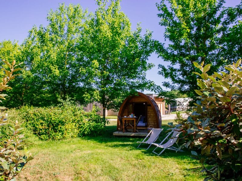Cabane en bois entourée de verdure, avec chaises longues pour se détendre.