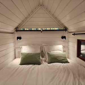 Chalet en bois avec lit douillet et éclairage coloré au plafond.