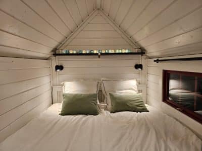 Chalet en bois avec lit douillet et éclairage coloré au plafond.