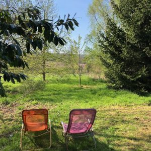 Hébergement insolite en pleine nature, chaises colorées face à un paysage verdoyant.