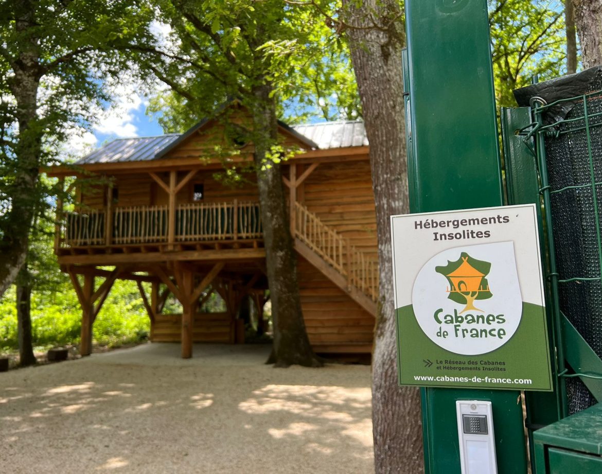 Cabane en bois perchée, entourée darbres, offrant un séjour insolite au cœur de la nature.