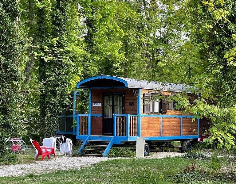 Charmante roulotte en bois, nichée dans un écrin de verdure, avec terrasse accueillante.
