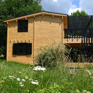Cabane en bois dans la nature, entourée de fleurs sauvages au Limousin.