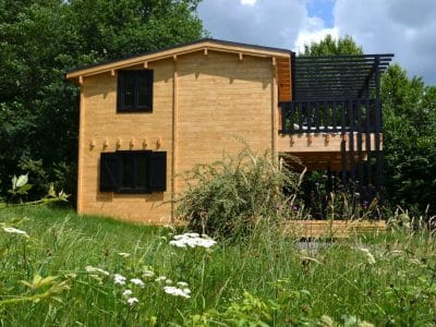 Cabane en bois dans la nature, entourée de fleurs sauvages au Limousin.