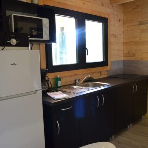 Hébergement insolite en Limousin : cuisine moderne en bois avec fenêtres lumineuses.