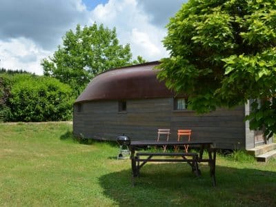 Hébergement insolite en Limousin : une cabane en bois avec un toit arrondi, jardin verdoyant.