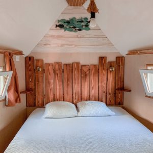 Chambre cocooning en bois dans un hébergement insolite au Limousin, avec lit confortable.