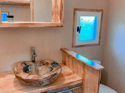 Salle de bain dun hébergement insolite en bois, avec un lavabo en bois sculpté.