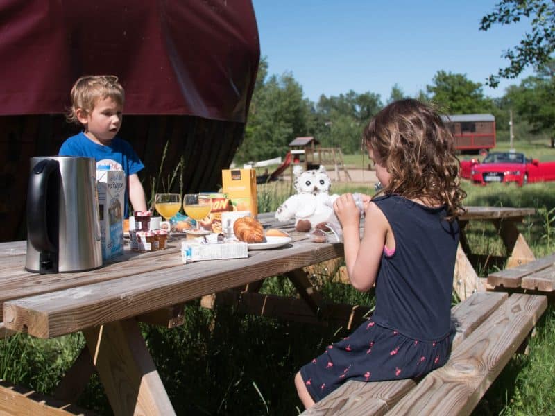 Séjour en roulotte, enfants savourant un petit-déjeuner en plein air.