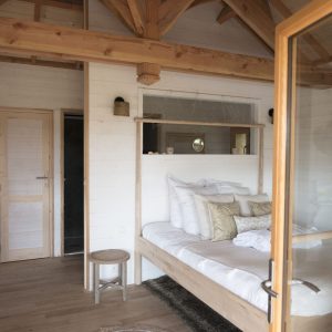 Hébergement insolite en Bretagne : cabane en bois avec lit douillet et décoration chaleureuse.