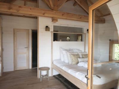 Hébergement insolite en Bretagne : cabane en bois avec lit douillet et décoration chaleureuse.