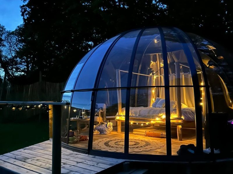 Hébergement insolite en Bretagne : bulle transparente avec guirlandes lumineuses.