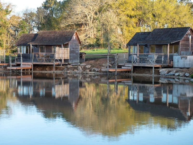 Chalets en bois au bord dun lac, entourés de verdure et de tranquillité.