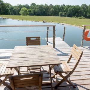 Hébergement insolite en Bretagne : terrasse en bois avec vue sur un étang paisible.