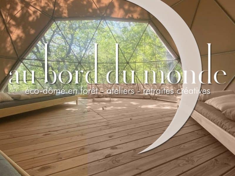 Éco-dôme en forêt avec un intérieur en bois et de grandes fenêtres lumineuses.
