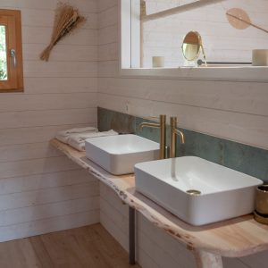 Salle de bain moderne en bois avec deux vasques, dans un hébergement insolite en Bretagne.