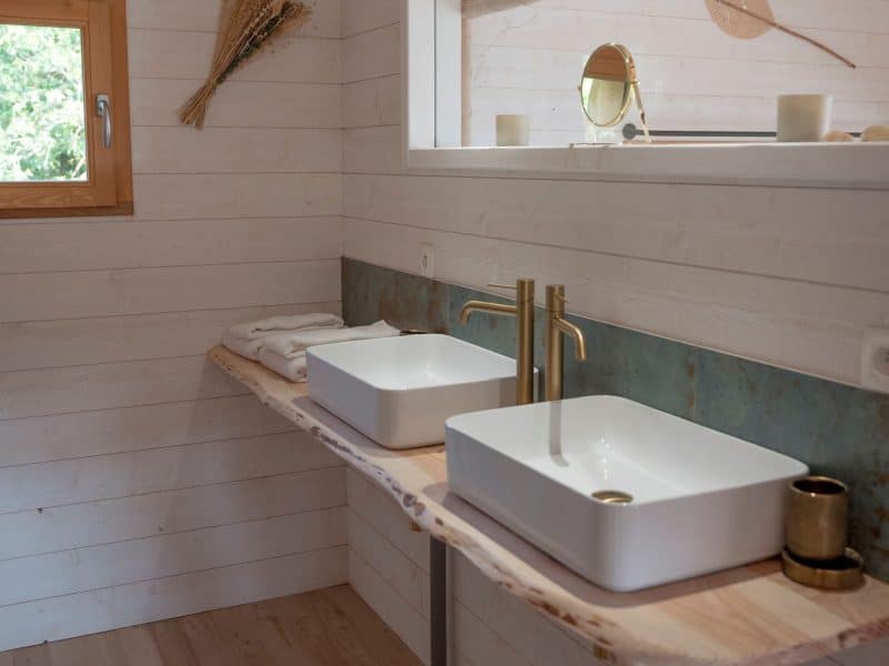 Salle de bain moderne dun chalet, avec deux lavabos élégants et un décor naturel.