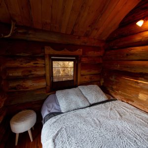 Cabane en bois dans les Midi-Pyrénées, intérieur chaleureux avec lit douillet.