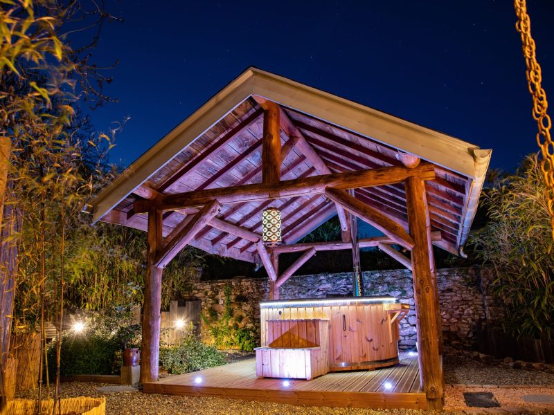 Hébergement insolite en Midi-Pyrénées, avec un spa sous un abri en bois illuminé.