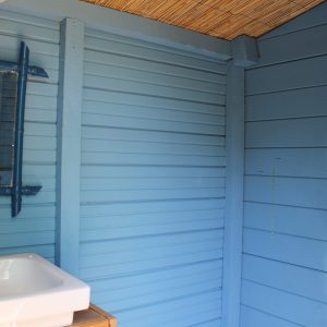 Cabane en bois avec douche, murs bleus et miroir, au cœur de la Provence.