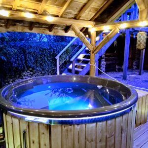Hébergement insolite en Midi-Pyrénées avec jacuzzi illuminé sous une pergola en bois.