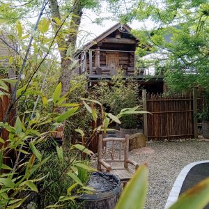 Cabane en bois perchée, entourée de verdure et dun jardin zen apaisant.