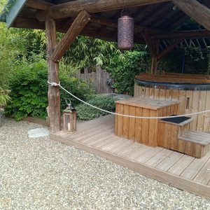 Hébergement insolite en Midi-Pyrénées avec un jacuzzi en bois entouré de verdure.