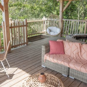 Hébergement insolite en Bretagne : cabane avec terrasse, fauteuil suspendu et jacuzzi.