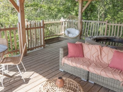 Hébergement insolite en Bretagne : cabane avec terrasse, fauteuil suspendu et jacuzzi.